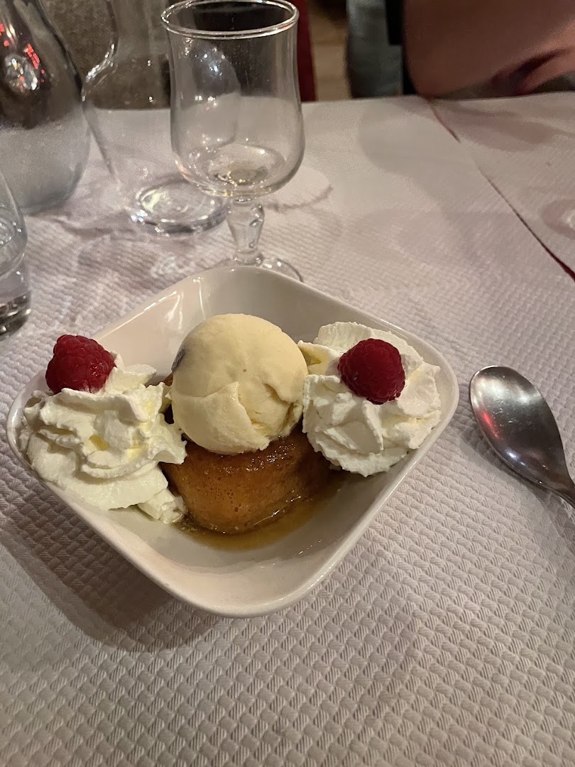A plated dessert with ice cream, cream and raspberries